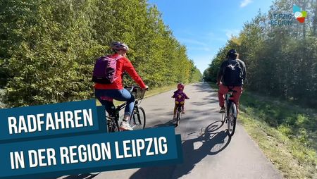Blick von hinten auf zwei Eltern mit einem Kind, die in der Leipzig Region Fahrrad fahren.