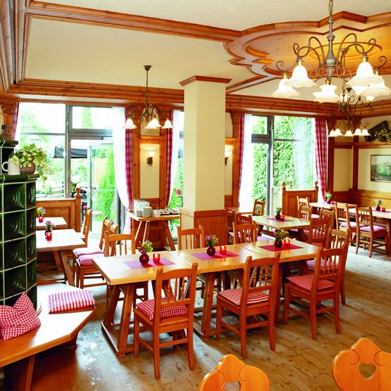 Das Bild zeigt ein Zimmer mit grünem Kachelofen und Bierhaus-Sitzecke