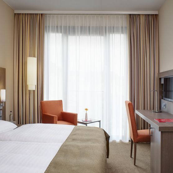 Bild zeigt geräumiges helles Doppelzimmer mit orangenen Design-Akzenten
