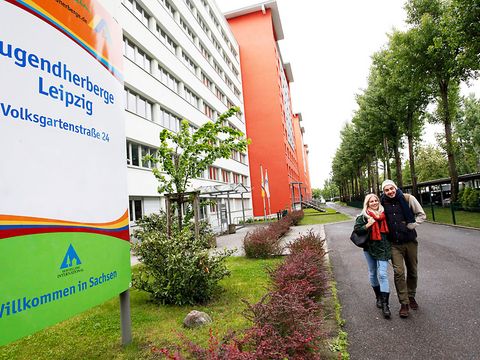 Ein Pärchen geht lächelnd an der Jugendherberge Leipzig entlang.