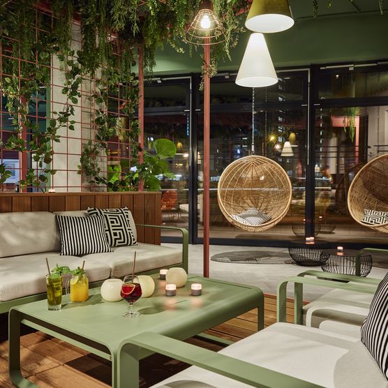 Das bild zeigt eine gemütliche Sitzecke im Hotel, der Einrichtungsstil ist urban jungle.