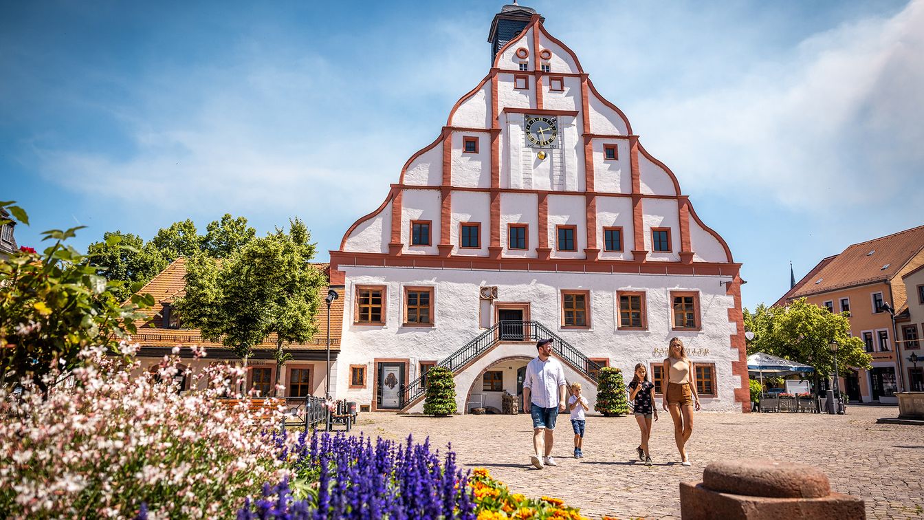 Eine Familie mit zwei Kindern vor dem Rathaus Grimma bei Sonnenschein.