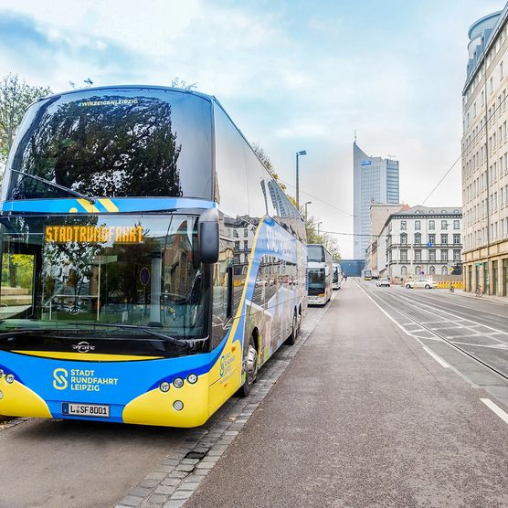 Ein blau-gelber Bus von Stadtrundfahrt Leipzig GmbH steht bei einer Bustour an der Start- und Endhaltestelle in der Goethestraße