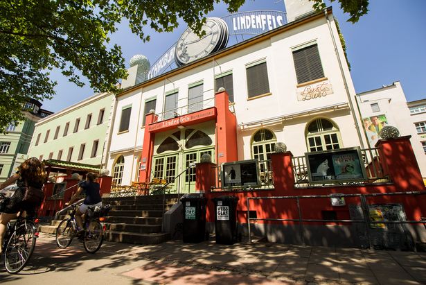 Auf dem weiß rotem Gebäude ist zwischen dem Namen eine große Uhr zu sehen, Kultur in Leipzig, Filmkunst 