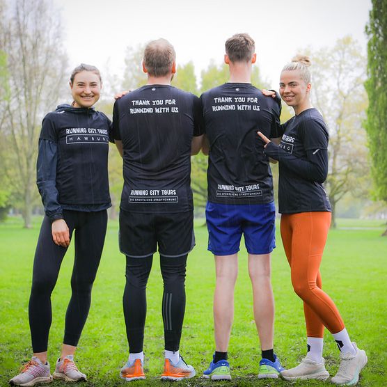 Vier Personen von Running City Tours stehen in Sportkleidung in einem Park