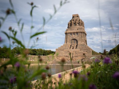 Seitlicher Blick auf das Völkerschlachtdenkmal Leipzig mit Blick auf eine Blumenwiese im Vordergrund des Bildes