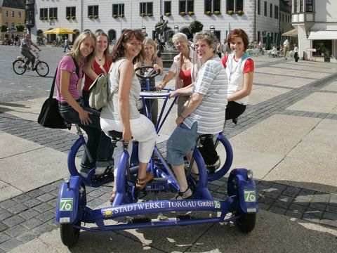 sechs Frauen sitzen auf dem Geschichtsrad auf dem Marktplatz in Torgau, Region, Leipzig, Radfahren, Fahrrad, Ausflugsziel