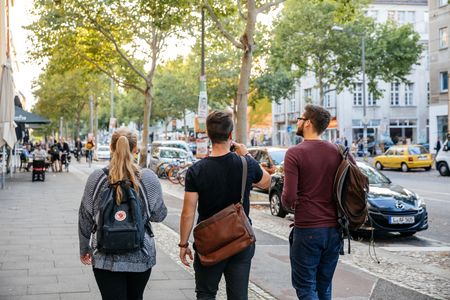 Drei junge Menschen laufen im Sommer die Karl-Heine-Straße in Leipzigs Szeneviertel Plagwitz entlang in Richtung Westen