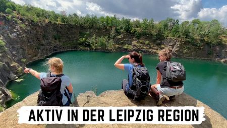 Drei Menschen schauen vom Steinbruch in Beucha auf den herzförmigen See an der Bergkirche in der Region Leipzig.