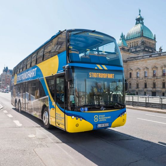 Ein blau-gelber Bus von Stadtrundfahrt Leipzig GmbH steht bei einer Bustour vor dem Bundesverwaltungsgericht