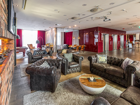 Lounge des Pentahotels Leipzig mit Sesseln und Aufzügen.