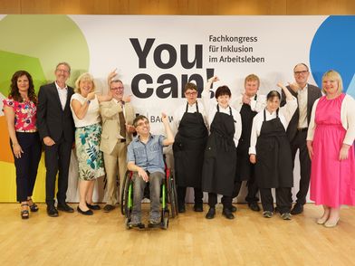 Eine Gruppe von Personen bei der Pressekonferenz zum Fachkongress ‚You can! 2026‘ zeigt gemeinsam auf die Logowand im Hintergrund für Tagung & Konferenz Leipzig Convention