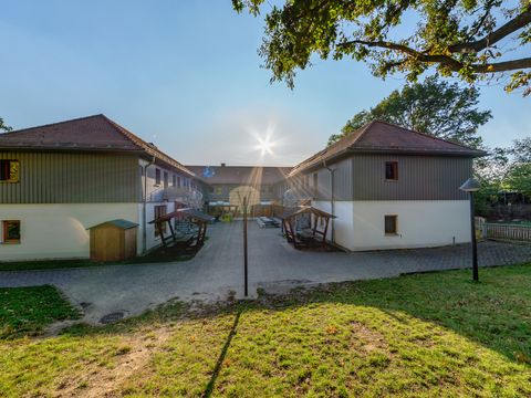 Blick auf die Jugendherberge Lausick mit Innenhof, umgeben von Bäumen und Grünflächen.