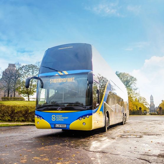 Ein blau-gelber Bus von Stadtrundfahrt Leipzig GmbH steht bei einer Bustour vor dem Völkerschlachtdenkmal