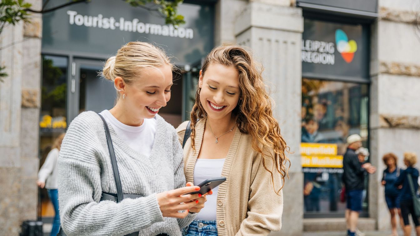 Zwei Frauen stehen vor der Tourist Information in Leipzig.