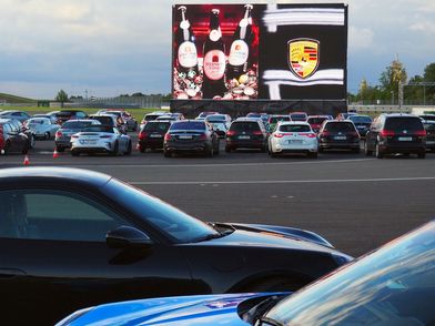 Autokino auf der Porsche Rundstrecke, zu sehen sind geparkte Autos & eine riesige Leinwand, über die der Imagefilm abgespielt wurde - Foto: Helge-Heinz Heinker