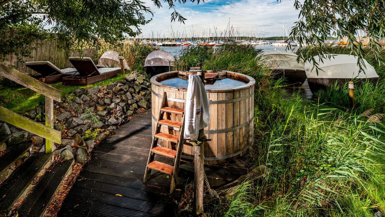 Ein fassähnliches Wasserbecken zum Abkühlen steht vor der idyllischen Kulisse des Cospudener Sees.