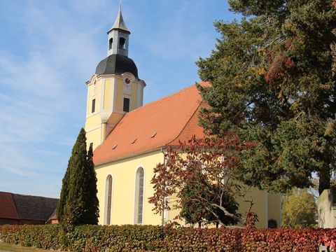 Das Bild zeigt die evangelische Dorfkirche mit Grünanlagen.