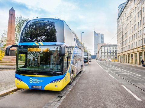 Ein blau-gelber Bus von Stadtrundfahrt Leipzig GmbH steht bei einer Bustour an der Start- und Endhaltestelle in der Goethestraße