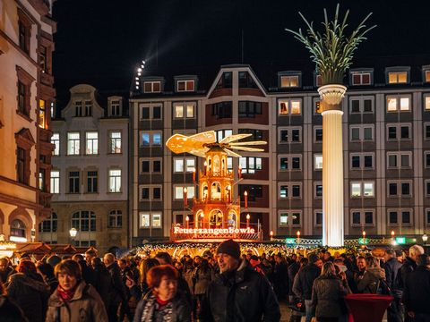 Ogromna piramida z napisem „Feuerzangenbowle” jaśnieje na tłumnie uczęszczanym Rynku Bożonarodzeniowym na dworze kościoła Nikolaikirchhof w Lipsku 
