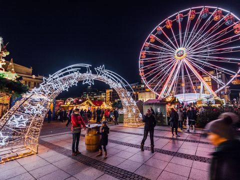 A Ferris wheel standing alongside numerous kiosks and stalls at the Christmas market on Augustusplatz