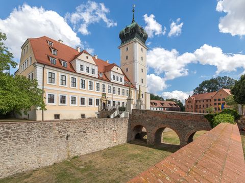 Das Bild Zeigt das kleine Barockschloss Delitzsch mit Graben und Zugangsbrücke.