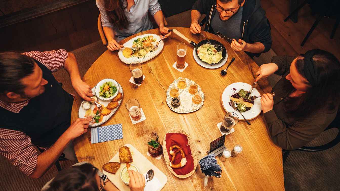Das Bild zeigt eine Freundesgruppe beim gemeinsamen Abendessen mit regionalen Spezialitäten.