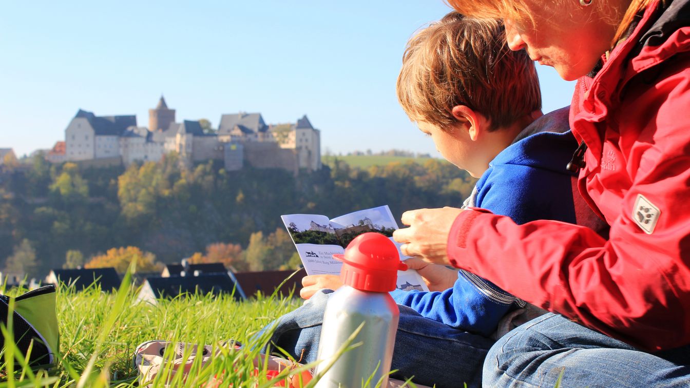 Familienpicknick mit Sohn und Mutter vor der eindrucksvollen Kulisse der mittelalterlichen Burg Mildenstein.