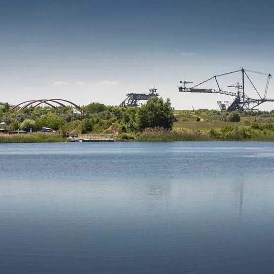 Das Bild zeigt den Markkleeberger See und am gegenüberliegenden Ufer kann man den Schaufelradbagger des Bergbau-Technik-Parks sehen.