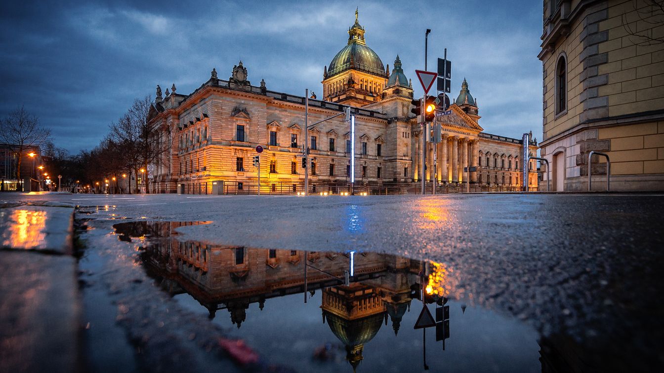 Das Bild zeigt die eindrucksvolle neo-barocke Außenansicht des Bundesverwaltungsgerichts, davor eine Pfütze.