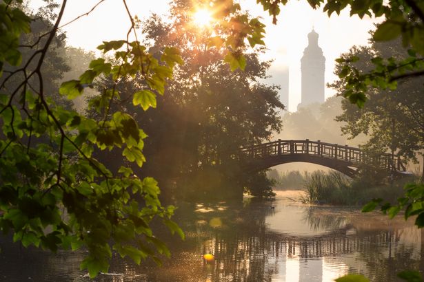 The sun rises over the bridge in Johannapark with a view of the new town hall and the Panorama Tower, spring in Leipzig, park