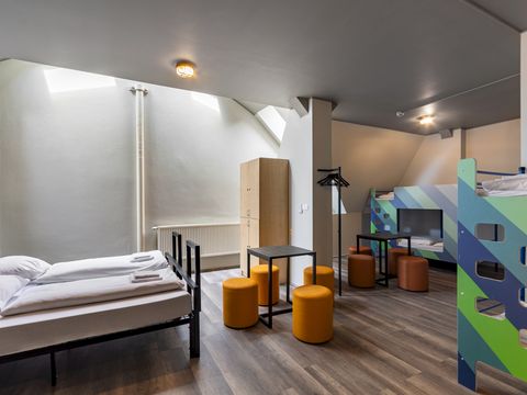 a&o Hostel Zimmer modern eingerichtet mit Doppelbett, Stockbetten und Sitzgelegenheiten für bis zu sechs Personen