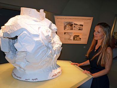 Blick in die Ausstellung des Geoportals "Erlebniswelt Kaolin", zu sehen ist eine Besucherin der Ausstellung neben einem großen Gebilde des Gesteins Kaolin, im Hintergrund sieht man eine Erklär-Tafel © Andreas Schmidt