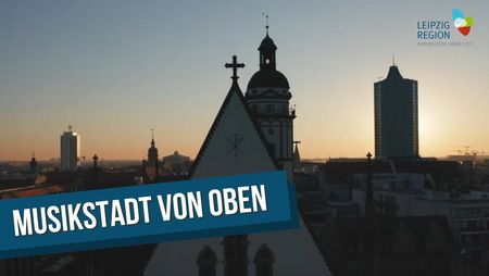 Das Video-Vorschaubild zeigt Dach und Turmspitze der Thomaskirche Leipzig, im Hintergrund ist die Silhouette von Leipzig mit dem City-Hochhaus zu erkennen