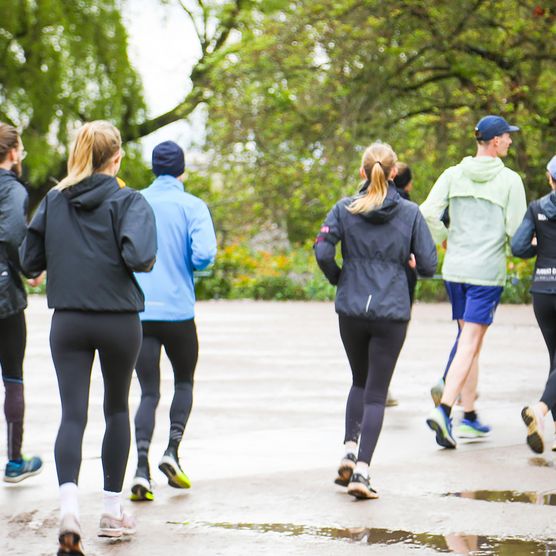Eine Gruppe von mindestens 7 Personen joggt bei über einen Asphaltweg
