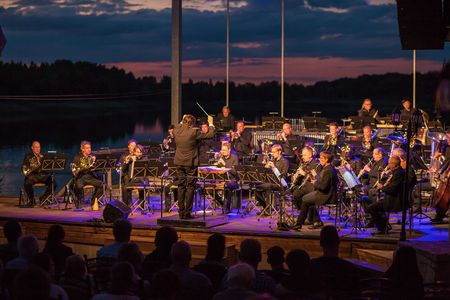 Das Orchester der Sächsischen Bläserphilharmonie spielt auf der Seebühne des Biedermeierstrands in Schkeuditz in der Region Leipzig. Im Hintergrund sieht man den Schladitzer See vor dem Nachthimmel