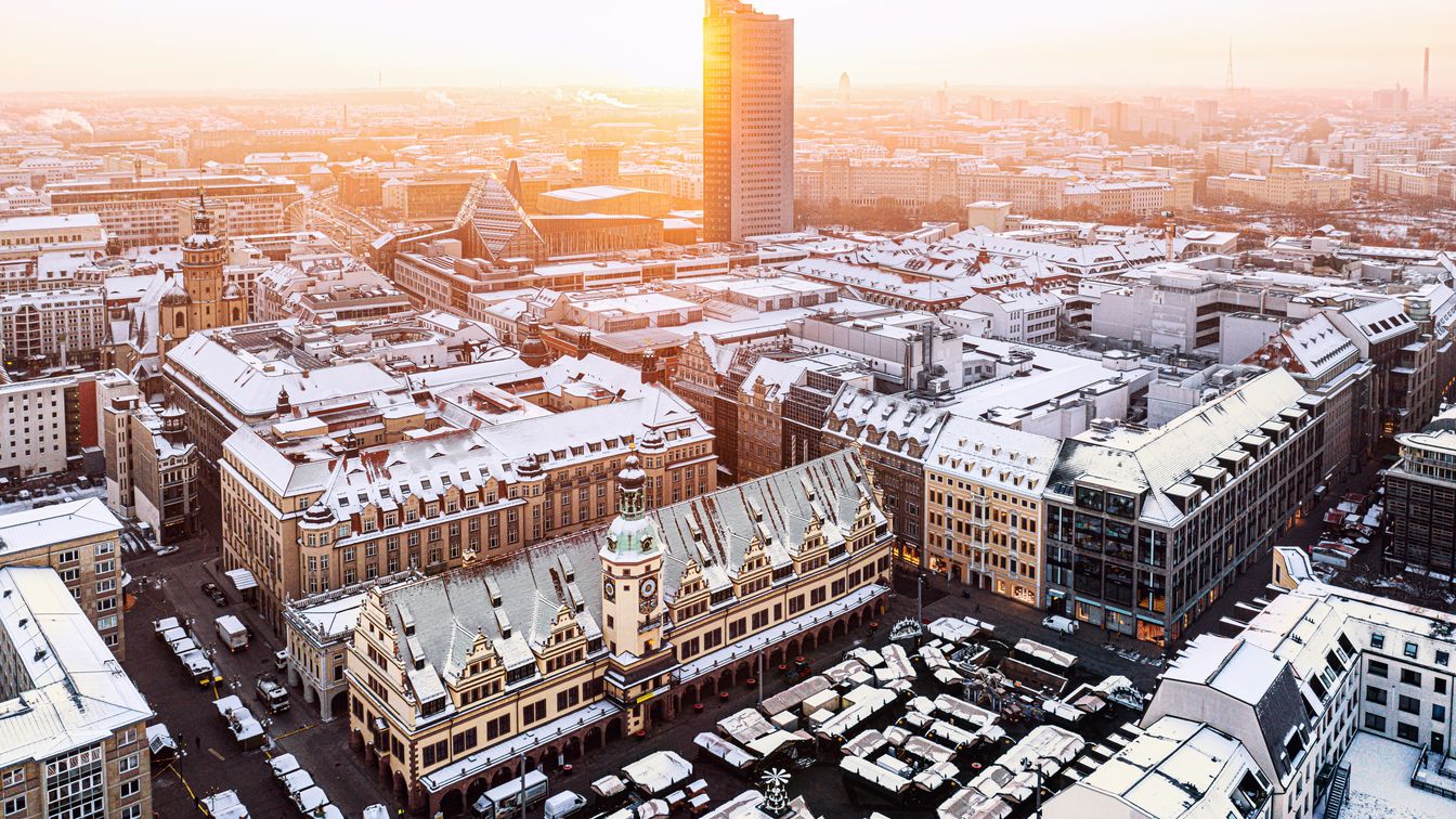 Die Sonne geht über den schneebedeckten Dächern der Leipziger Innenstadt im Winter auf.