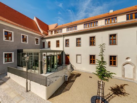 Blick auf ein modernes Gebäude mit grau-weißer Fassade und verglastem Eingang im Innenhof.