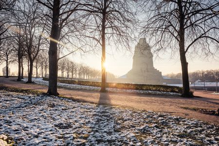 Blick auf die winterliche Umgebung mit dem monumentalen Völkerschlachtdenkmal bei Sonnenaufgang im Hintergrund.