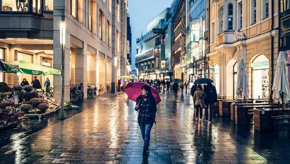 Eine Frau mit einem lila Regenschirm schlendert durch die Leipziger Innenstadt, Shoppen in Leipzig, Freizeit