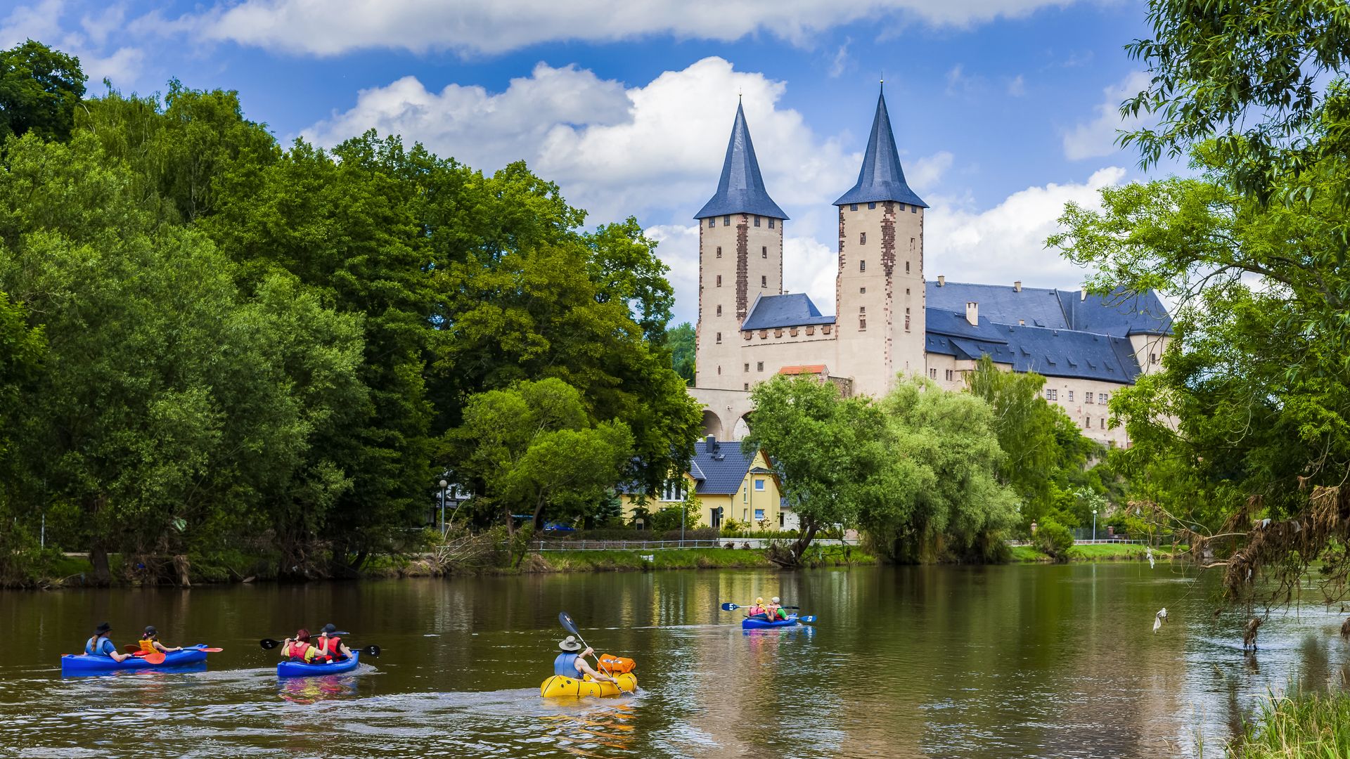 Water tourers canoeing past Rochlitz Castle on the river Zwickau Mulde.