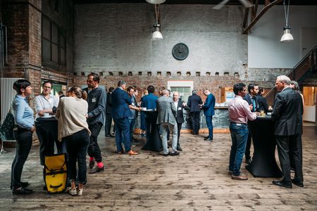 Leipzig Art Power Plant tijdens een evenement. Mensen in zakelijke outfits staan ​​aan bartafels.