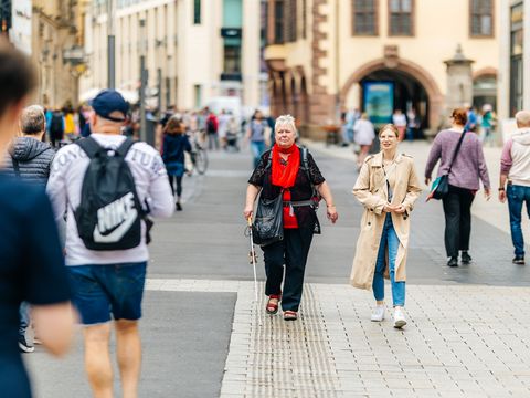Mithilfe des Blindenleitsystems findet sich die sehbehinderte Frau in der Innenstadt gut zurecht.