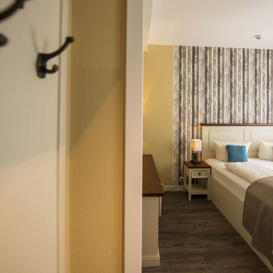 DAs Bild zeigt ein geräumiges, schlicht aber hell eingerichtetes Schlafzimmer.