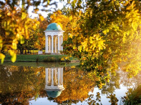 Der Musentempel im agra-Park Markkleeberg spiegelt sich im See, dazu glizert die warme Herbstsonne über die gelbgoldene Szenerie, Leipzig Region