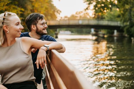 Eine junge Frau und ein junger Mann sitzen bei Sonnenuntergang auf einem Motorboot vom Stadthafen Leipzig und genießen eine Rundfahrt auf der Weißen Elster