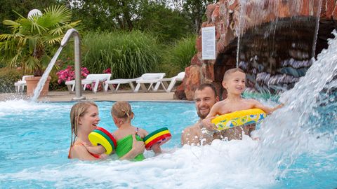 Eine lachende Familie mit Kindern hat Spaß in einem Pool des Freizeitbad Riff, in dessen Resort Familien für einen Kurzurlaub auch übernachten können.