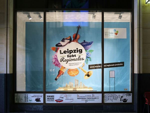 Goethe Chocolaterie - Schaufenster mit Schokoladen-Skyline, zu sehen ist das Key Visual der LTM-Kampagne "Leipzig liebt Regionales" im Schaufenster der Goethe Chocolaterie in der Marktgalerie sowie die Leipzig-Skyline aus Schokolade - Foto: Andreas Schmidt