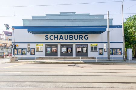Man sieht das blau-weiße Gebäude mit vielen Filmplakaten an der Fassade.