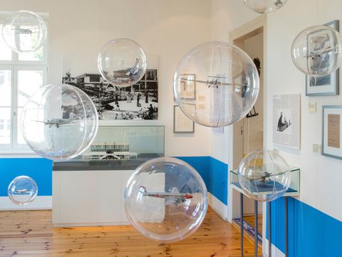 Das Bild zeigt einen Ausstellungsrauf in welchem in klarsichtigen Plastik-Blasen Modellflugzeuge in der Luft schweben.